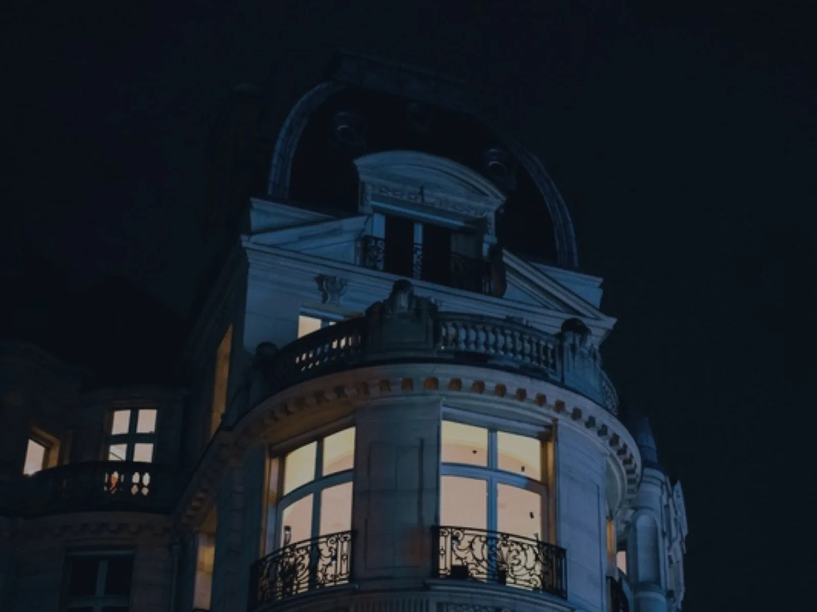 Immeuble ancien à rotonde, fenêtres éclairées de nuit